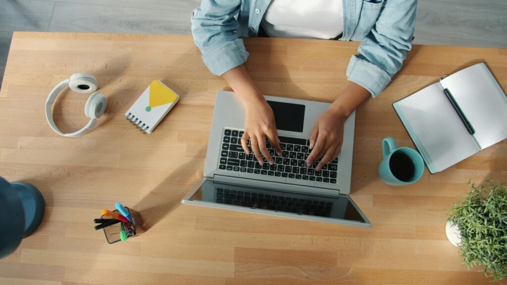 Top-down view of a person working on a laptop at a neat desk with accessories.